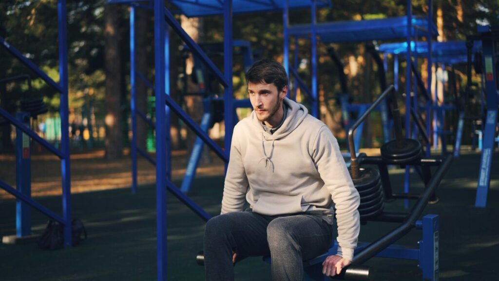 Hombre sentado en un banco del gimnasio con gesto pensativo tras entrenar, por qué no pierdo grasa aunque esté en déficit